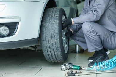 Photo of Mechanic changing tire at car service, closeup