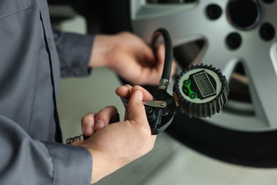 Photo of Mechanic inflating new tire at car service, closeup