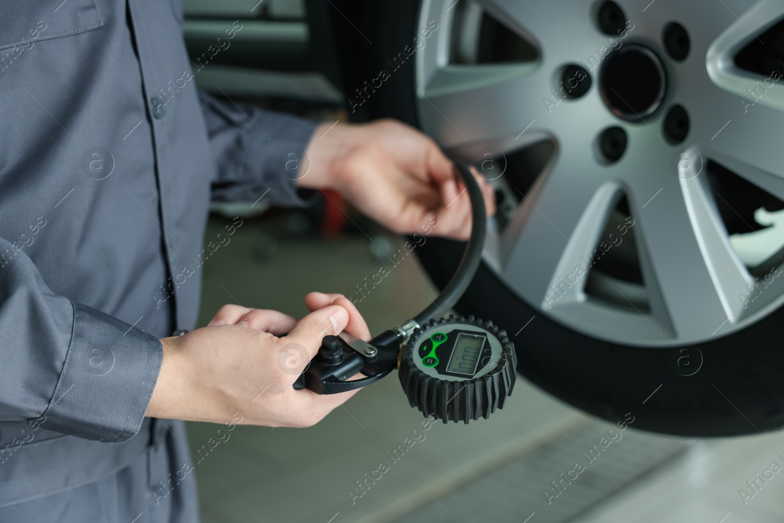 Mechanic inflating new tire at car service, closeup Photo of Mechanic inflating new tire at car service, closeup