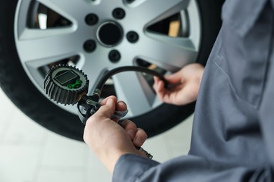 Photo of Mechanic inflating new tire at car service, closeup