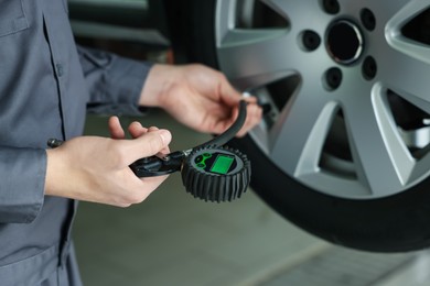 Photo of Mechanic inflating new tire at car service, closeup