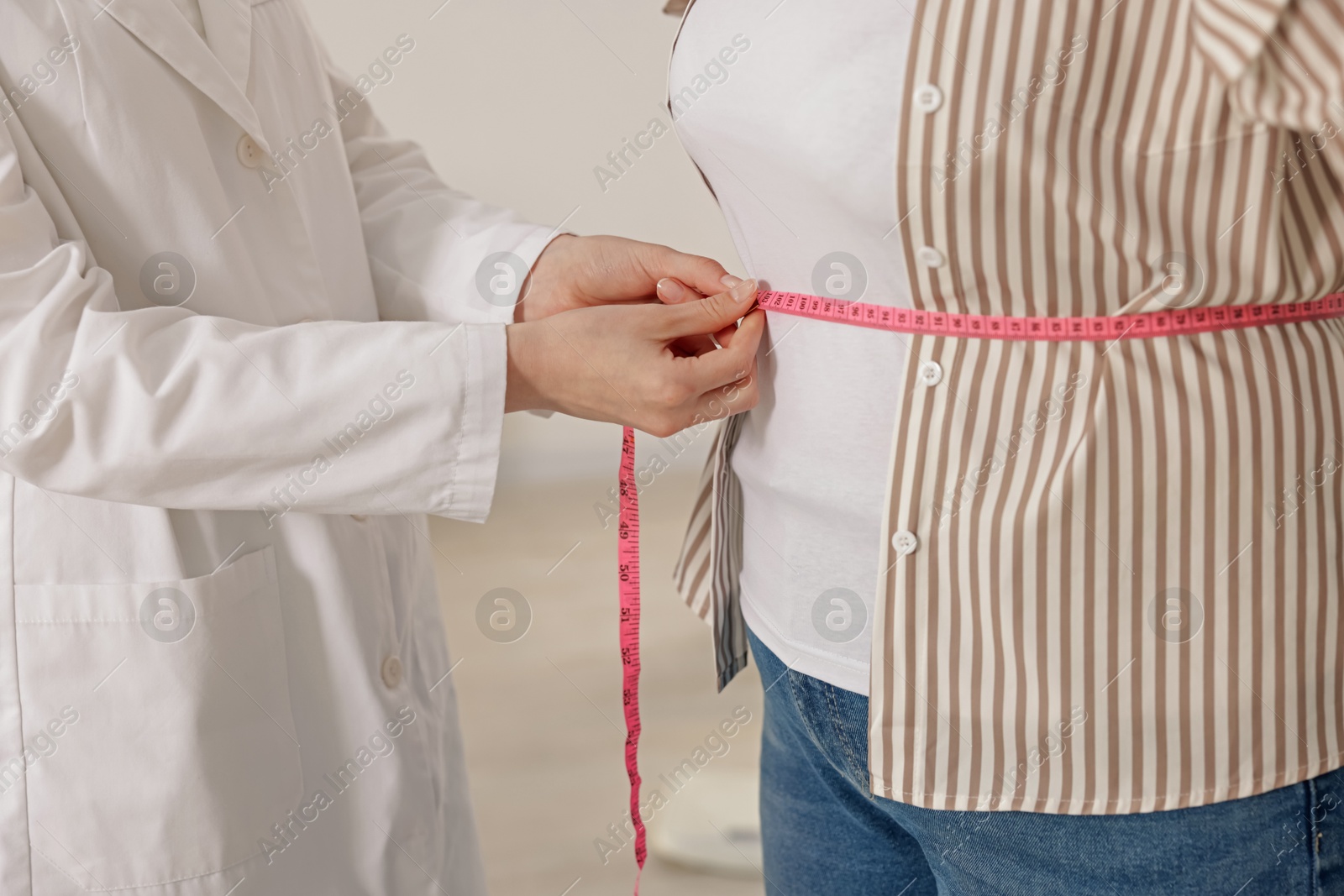 Weight loss. Nutritionist measuring overweight woman's waist with tape in clinic Photo of Weight loss. Nutritionist measuring overweight woman's waist with tape in clinic