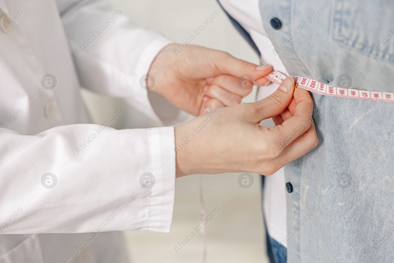 Weight loss. Nutritionist measuring overweight woman's waist with tape in clinic, closeup Photo of Weight loss. Nutritionist measuring overweight woman's waist with tape in clinic, closeup