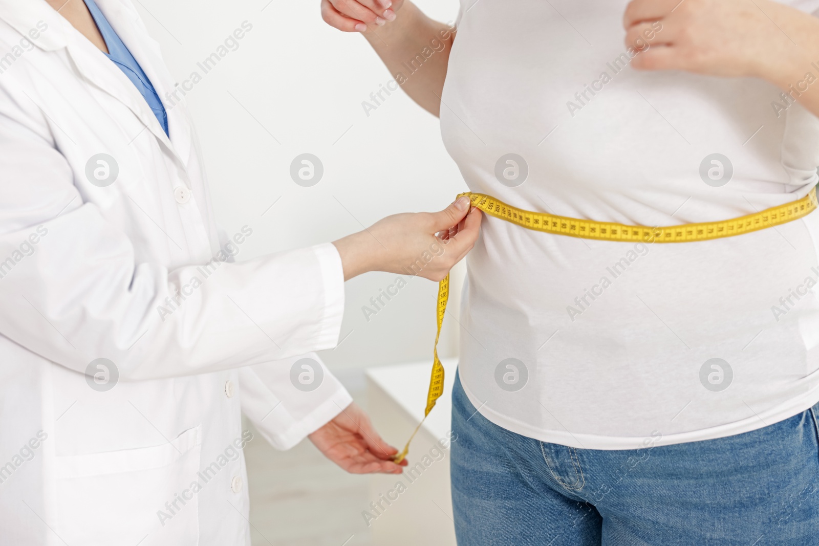 Weight loss. Nutritionist measuring overweight woman's waist with tape in clinic, closeup Photo of Weight loss. Nutritionist measuring overweight woman's waist with tape in clinic, closeup