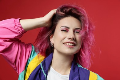 Photo of Beautiful woman with pink dyed hair on red background