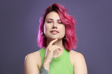 Photo of Beautiful woman with pink dyed hair on violet background