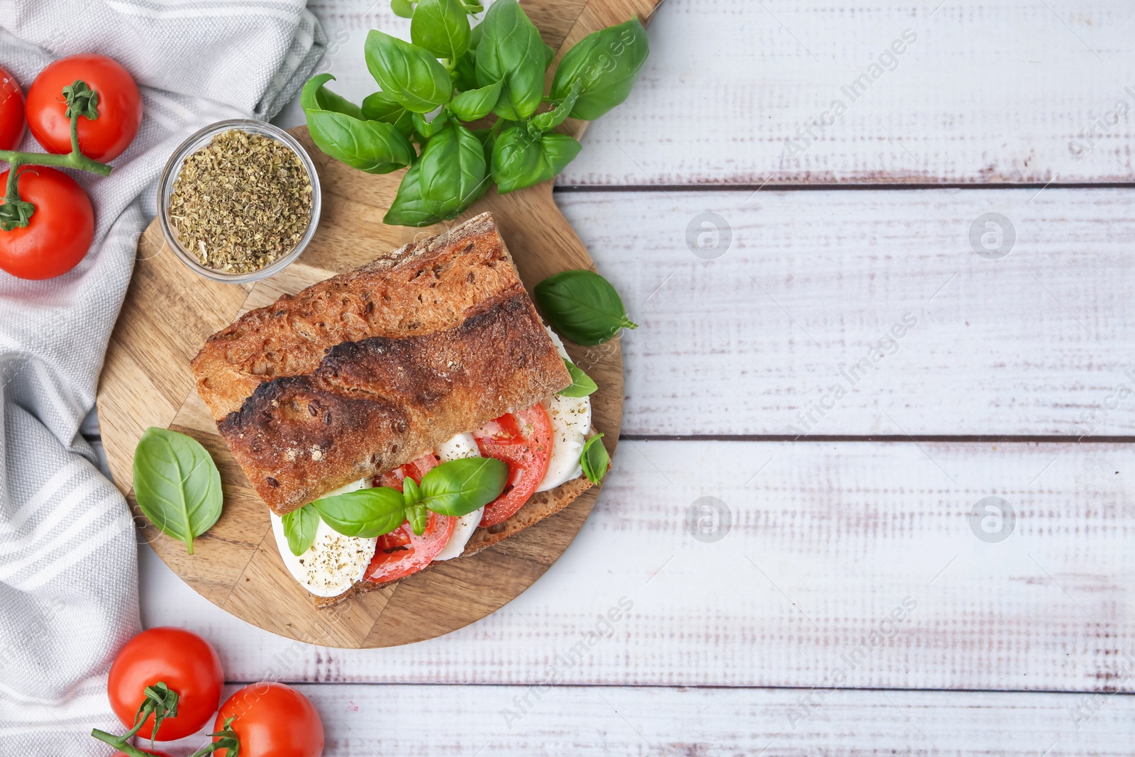 Tasty sandwich with mozzarella cheese, tomatoes and basil on white wooden table, flat lay. Space for text Photo of Tasty sandwich with mozzarella cheese, tomatoes and basil on white wooden table, flat lay. Space for text