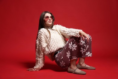 Photo of Fashionable portrait of beautiful woman in stylish outfit on red background