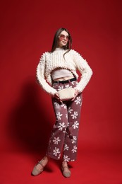 Photo of Fashionable full-length portrait of beautiful woman in stylish outfit on red background