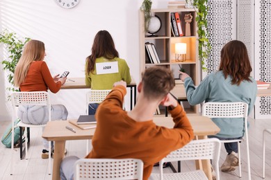 Photo of Schoolmates bullying teenage girl with sign You Loser on her back at school