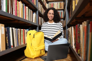 Photo of Woman with book studying near shelves in public library