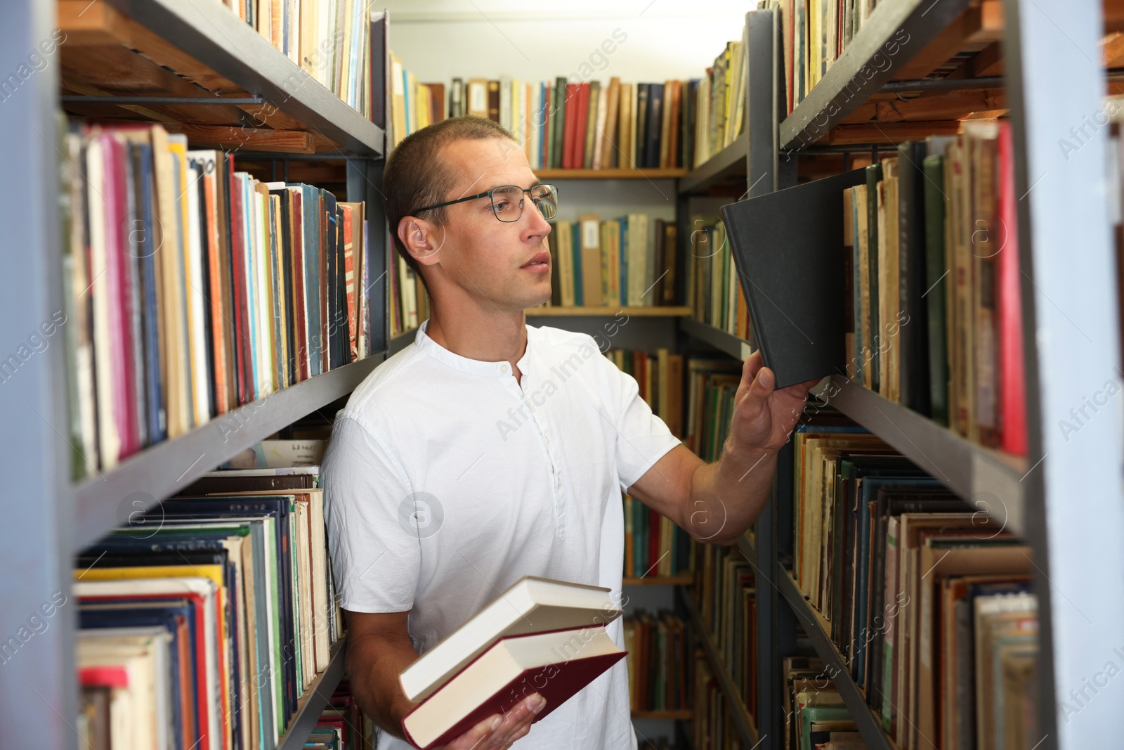 Man choosing book from shelf in public library Photo of Man choosing book from shelf in public library