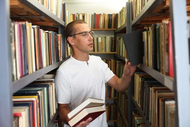 Photo of Man choosing book from shelf in public library