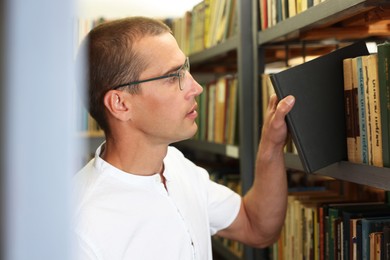 Photo of Man choosing book from shelf in public library