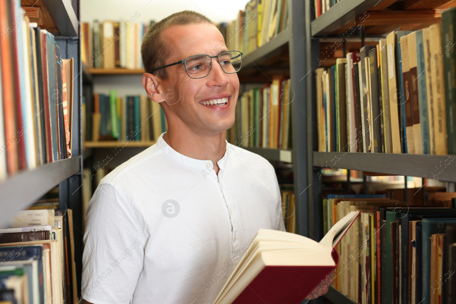 Man with book near shelves in public library Photo of Man with book near shelves in public library