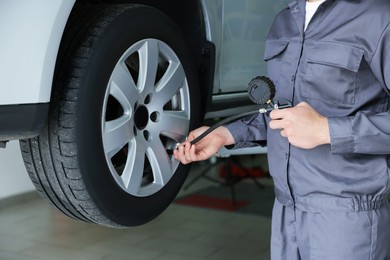 Photo of Mechanic inflating new tire at car service, closeup