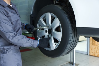 Photo of Mechanic changing tire at car service, closeup