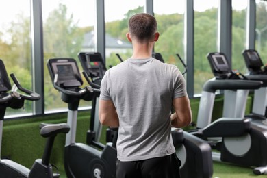 Photo of Personal trainer in sport center, back view