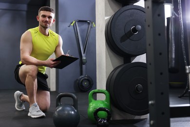 Photo of Personal trainer with clipboard and sports equipment in gym