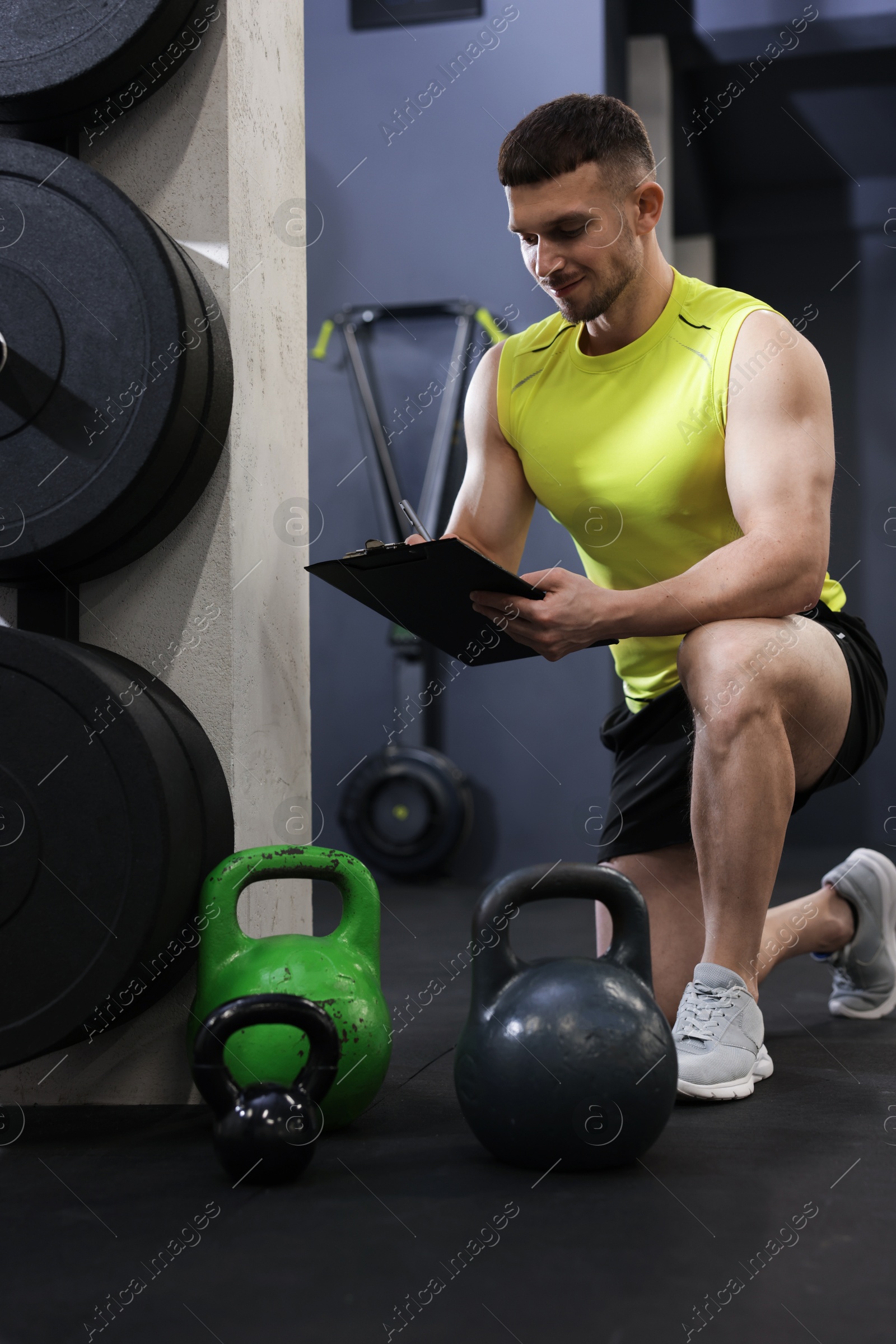 Personal trainer with clipboard and sports equipment in gym Photo of Personal trainer with clipboard and sports equipment in gym