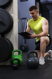 Photo of Personal trainer with clipboard and sports equipment in gym