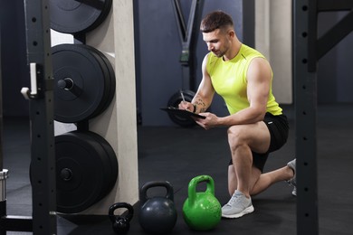 Photo of Personal trainer with clipboard and sports equipment in gym