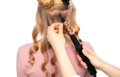 Photo of Hairdresser curling woman's hair on white background, back view