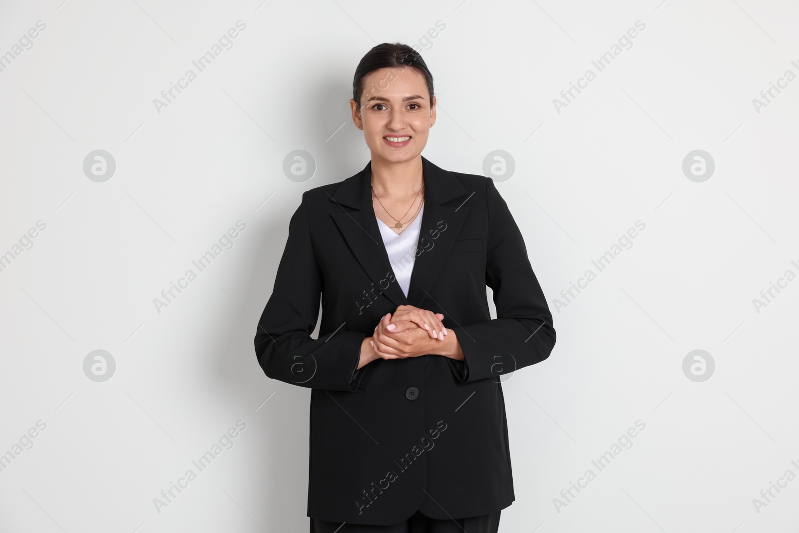 Confident business woman in suit on light background Photo of Confident business woman in suit on light background