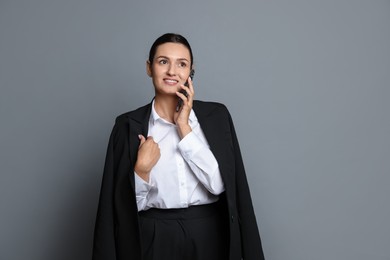 Photo of Confident business woman in suit talking on phone against grey background
