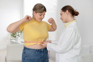 Photo of Weight loss. Nutritionist measuring overweight woman's waist with tape in clinic