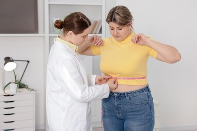 Photo of Weight loss. Nutritionist measuring overweight woman's waist with tape in clinic