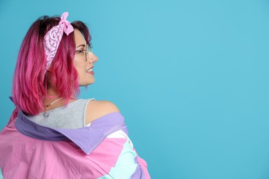 Photo of Beautiful woman with pink dyed hair in glasses on light blue background, space for text