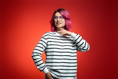Photo of Beautiful woman with pink dyed hair in glasses on red gradient background