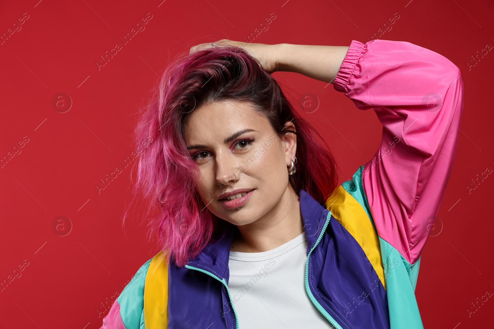 Beautiful woman with pink dyed hair on red background Photo of Beautiful woman with pink dyed hair on red background