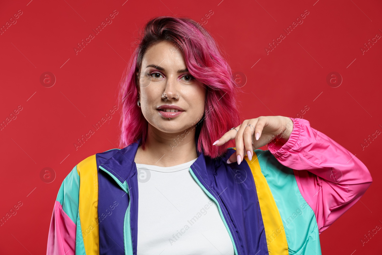 Beautiful woman with pink dyed hair on red background Photo of Beautiful woman with pink dyed hair on red background