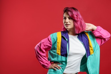 Photo of Beautiful woman with pink dyed hair on red background, space for text