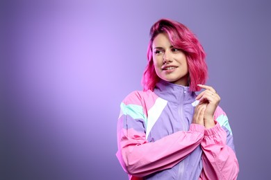 Photo of Beautiful woman with pink dyed hair on violet background, space for text