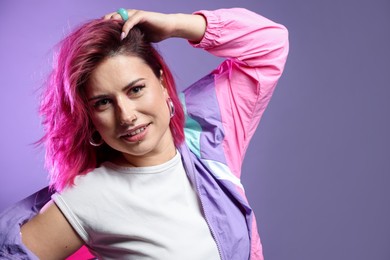 Photo of Beautiful woman with pink dyed hair on violet gradient background