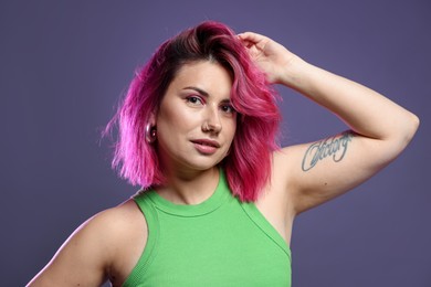Photo of Beautiful woman with pink dyed hair on violet background