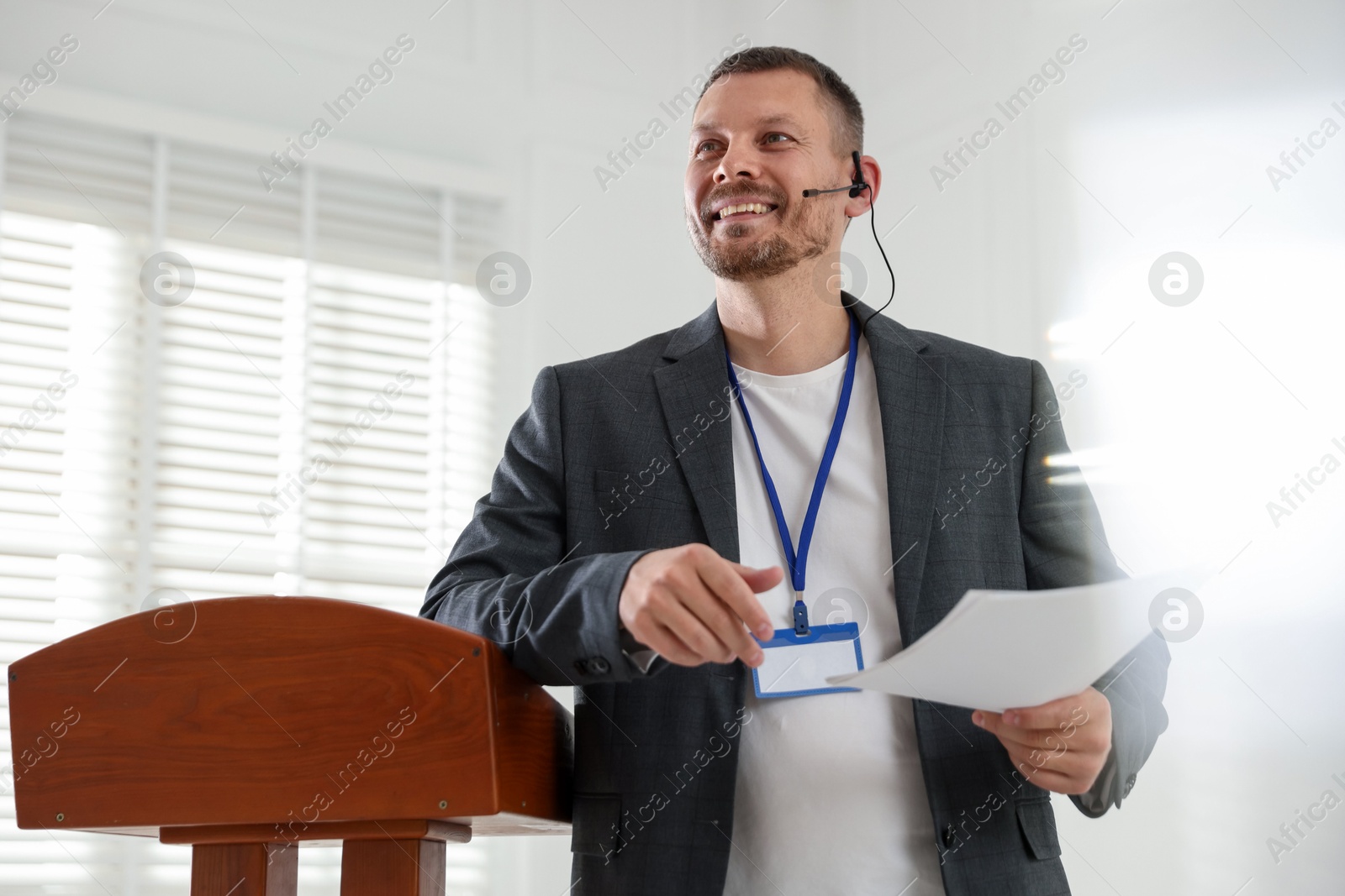 Man giving public speech with microphone at lectern indoors Photo of Man giving public speech with microphone at lectern indoors