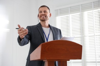 Photo of Man giving public speech with microphone at lectern indoors