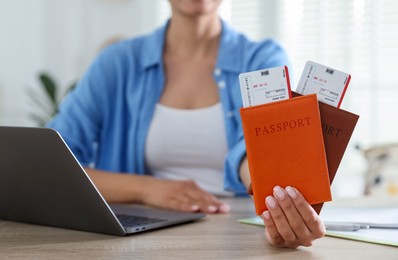 Photo of Travel agent with passports and tickets at wooden table in office, closeup