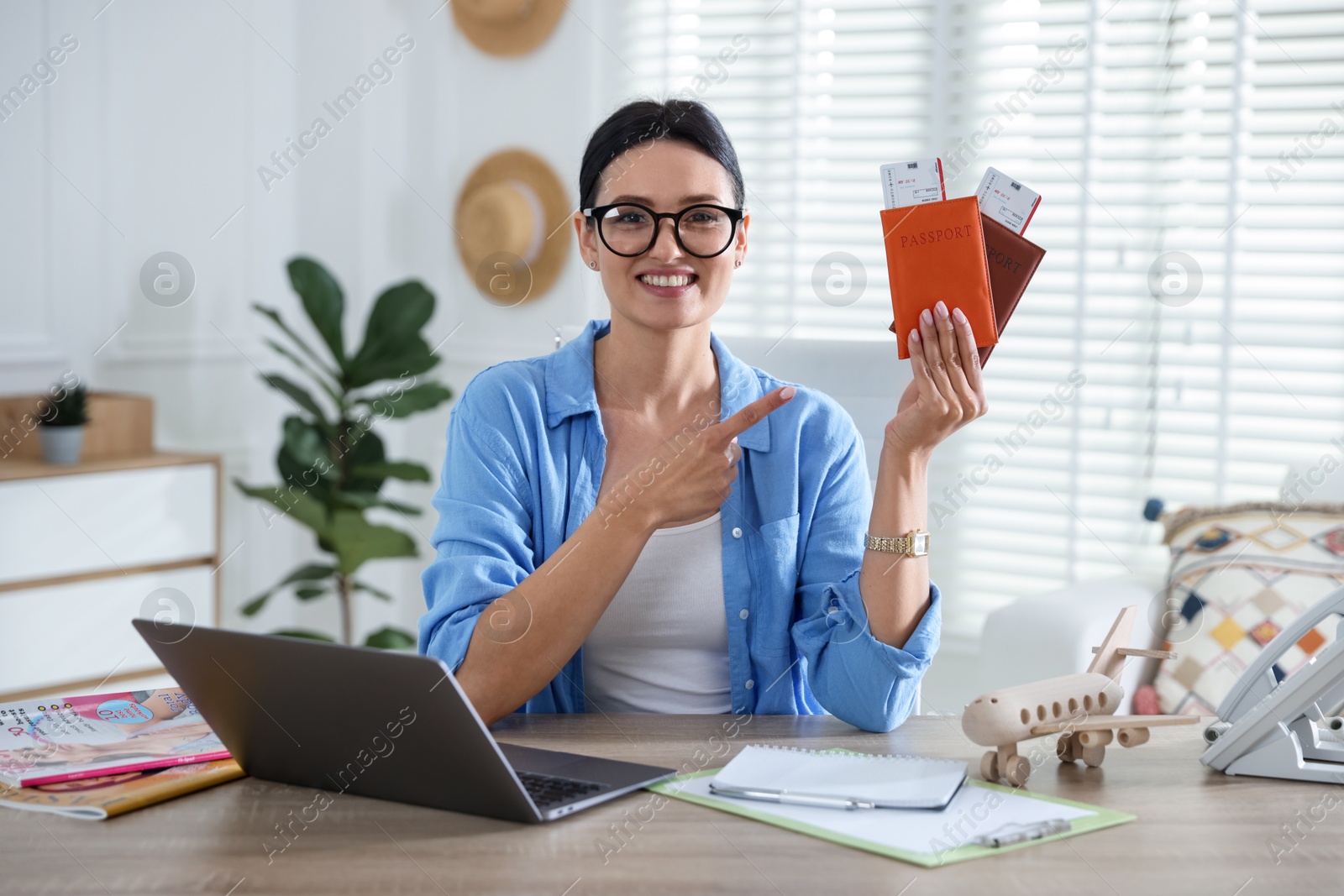 Travel agent with passports and tickets at wooden table in office Photo of Travel agent with passports and tickets at wooden table in office