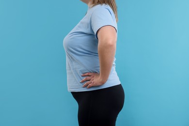 Photo of Weight loss. Plus size woman on light blue background, closeup