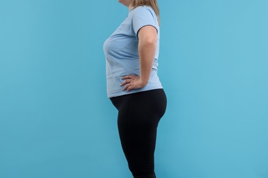 Photo of Weight loss. Plus size woman on light blue background, closeup