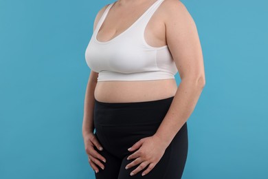 Photo of Weight loss. Plus size woman on light blue background, closeup