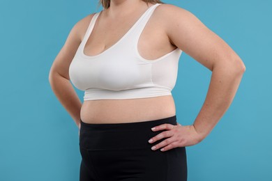 Photo of Weight loss. Plus size woman on light blue background, closeup