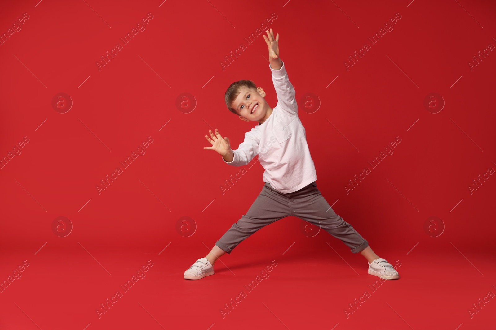 Happy little boy dancing on red background, space for text Photo of Happy little boy dancing on red background, space for text