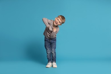 Photo of Happy little boy dancing on light blue background