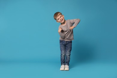 Photo of Happy little boy dancing on light blue background, space for text